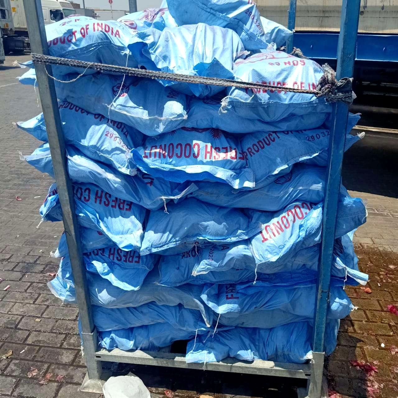 Branded 'Fresh Coconut' sacks stacked on a cart, ready to load